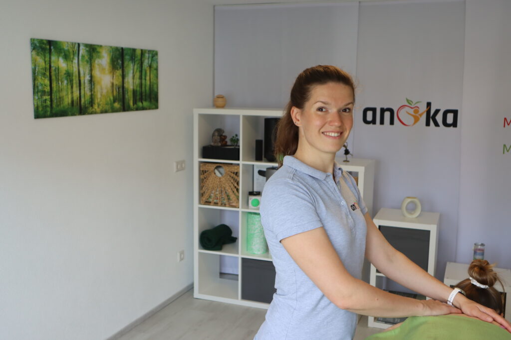 sporttherapeutische Praxis in Marbach: zu sehen ist Therapeutin Anna Kolb-Kubis in ihren Praxisräumen bei einer Massagetherapie. Im Hintergrund ist das Logo von anka Gesundheitssport zu sehen. 